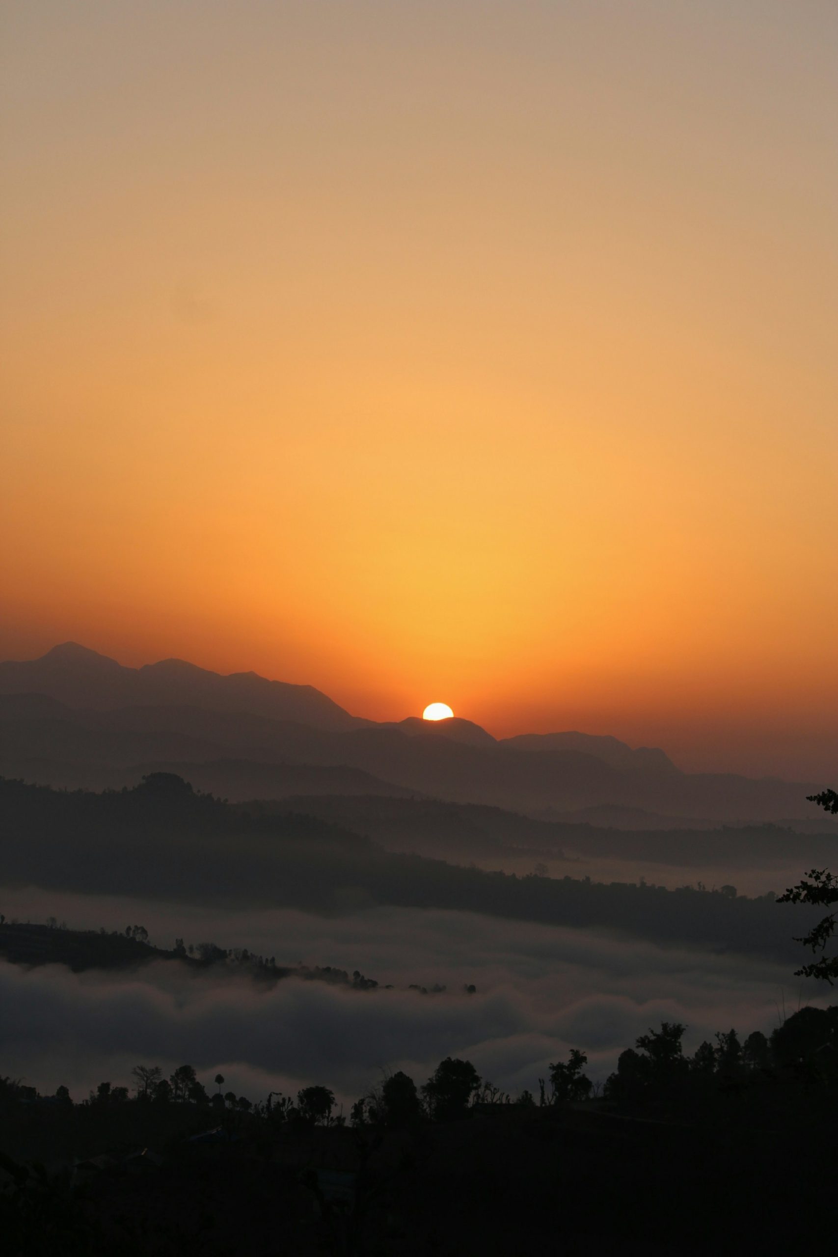 Low sun over misty layered mountain ridges